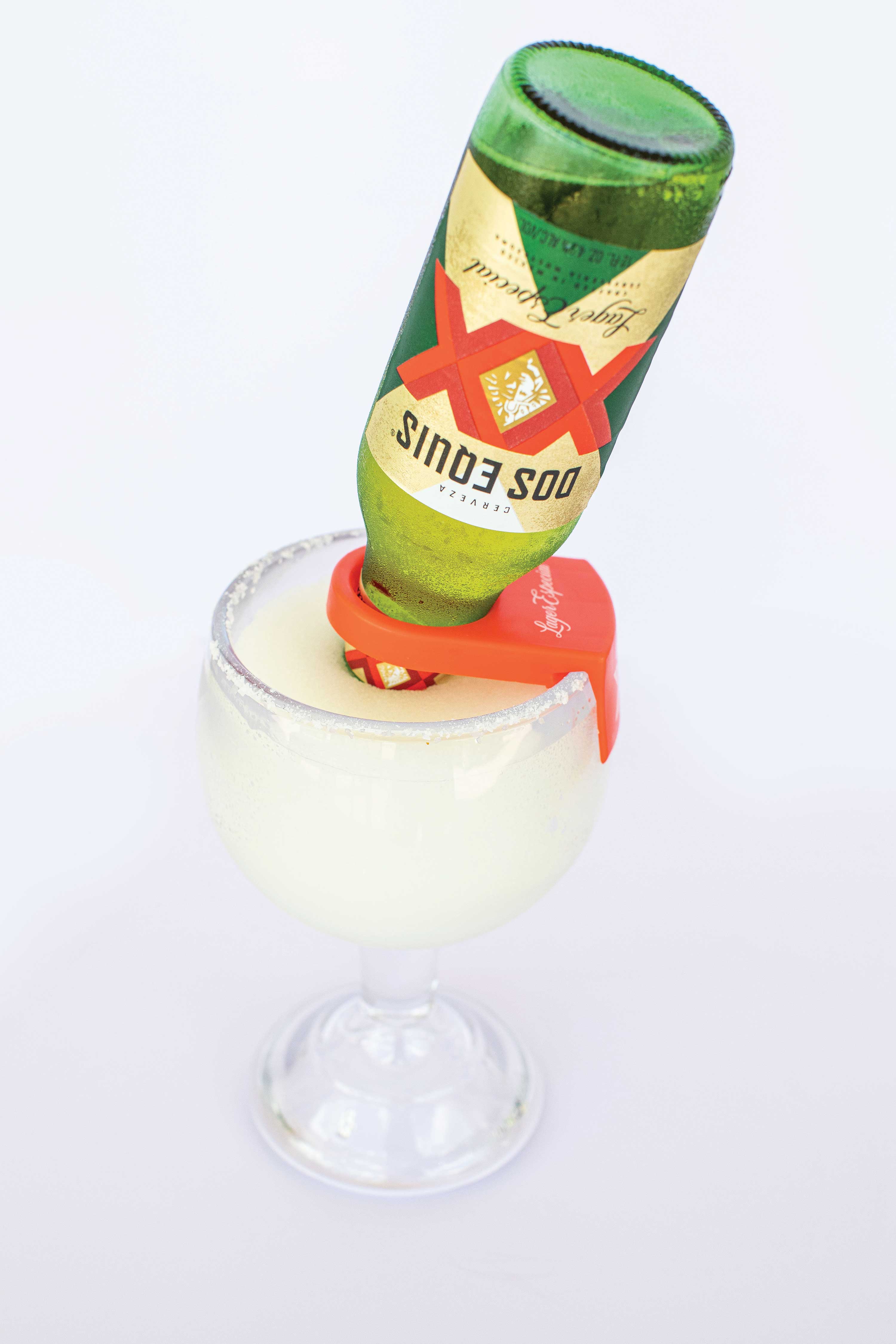 Image: A large glass is filled with icy margarita. A green beer bottle is set upside-down into the glass.